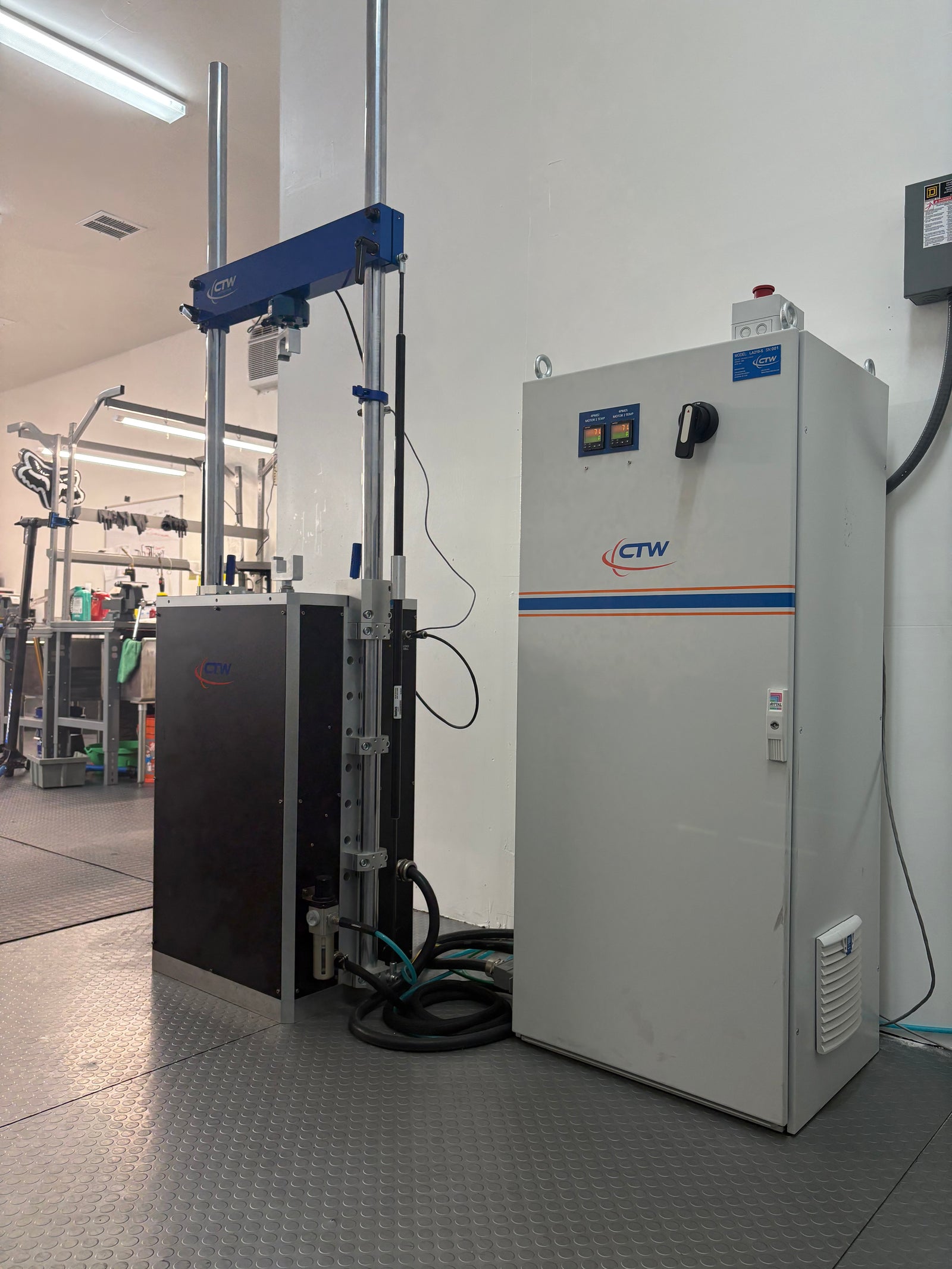 Industrial MTB suspension dyno with a control panel on a wall.