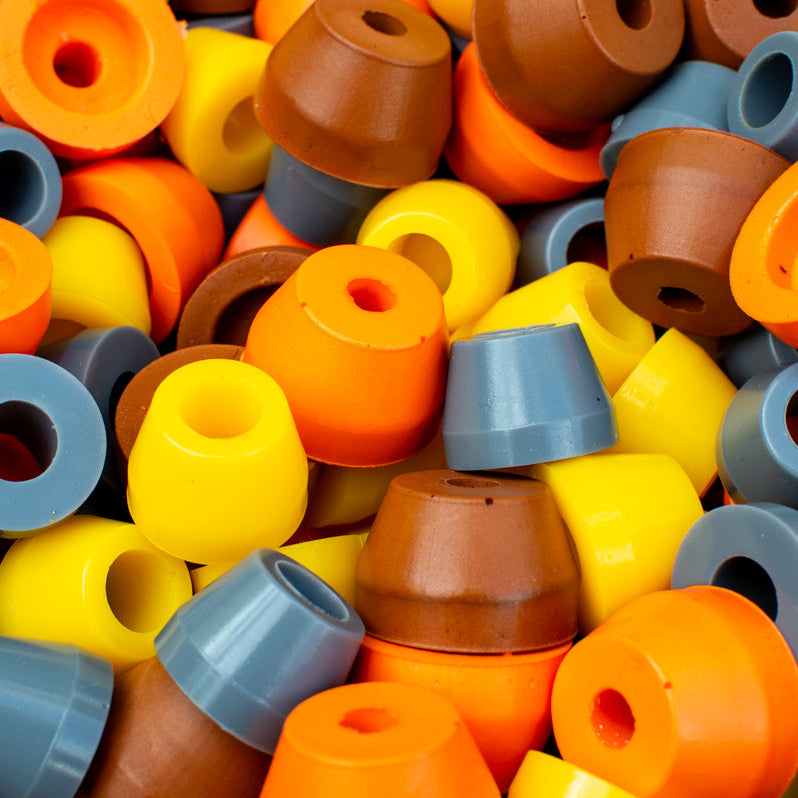 A collection of mountain bike bump stops in various colors including black, gray, yellow, orange, and brown.