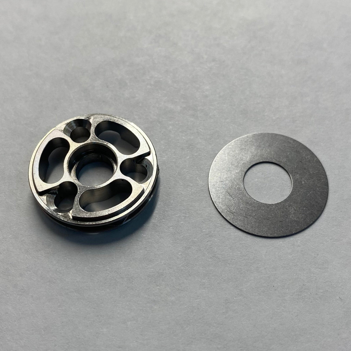 A metal base valve piston and a check shim from a bicycle shock absorber.