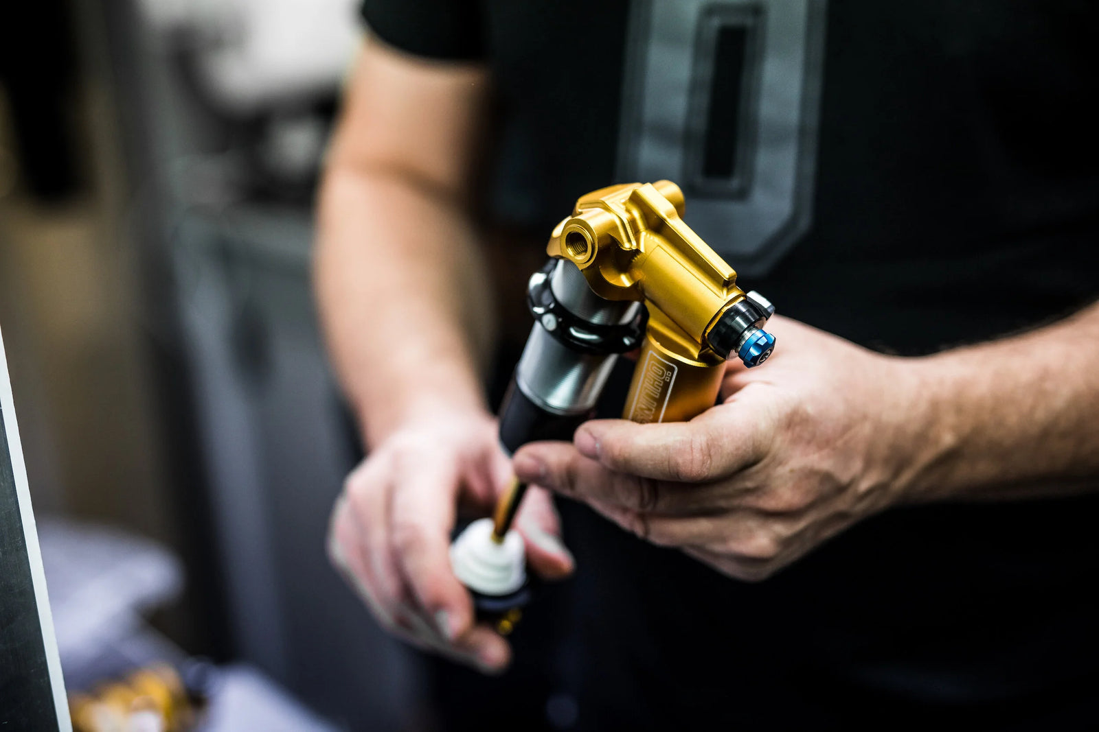 Person holding a MTB suspension with gold and black design